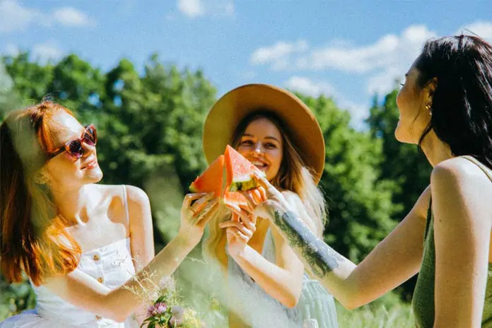 Happy Women Holding Slices of Watermelon While Looking at Each Other